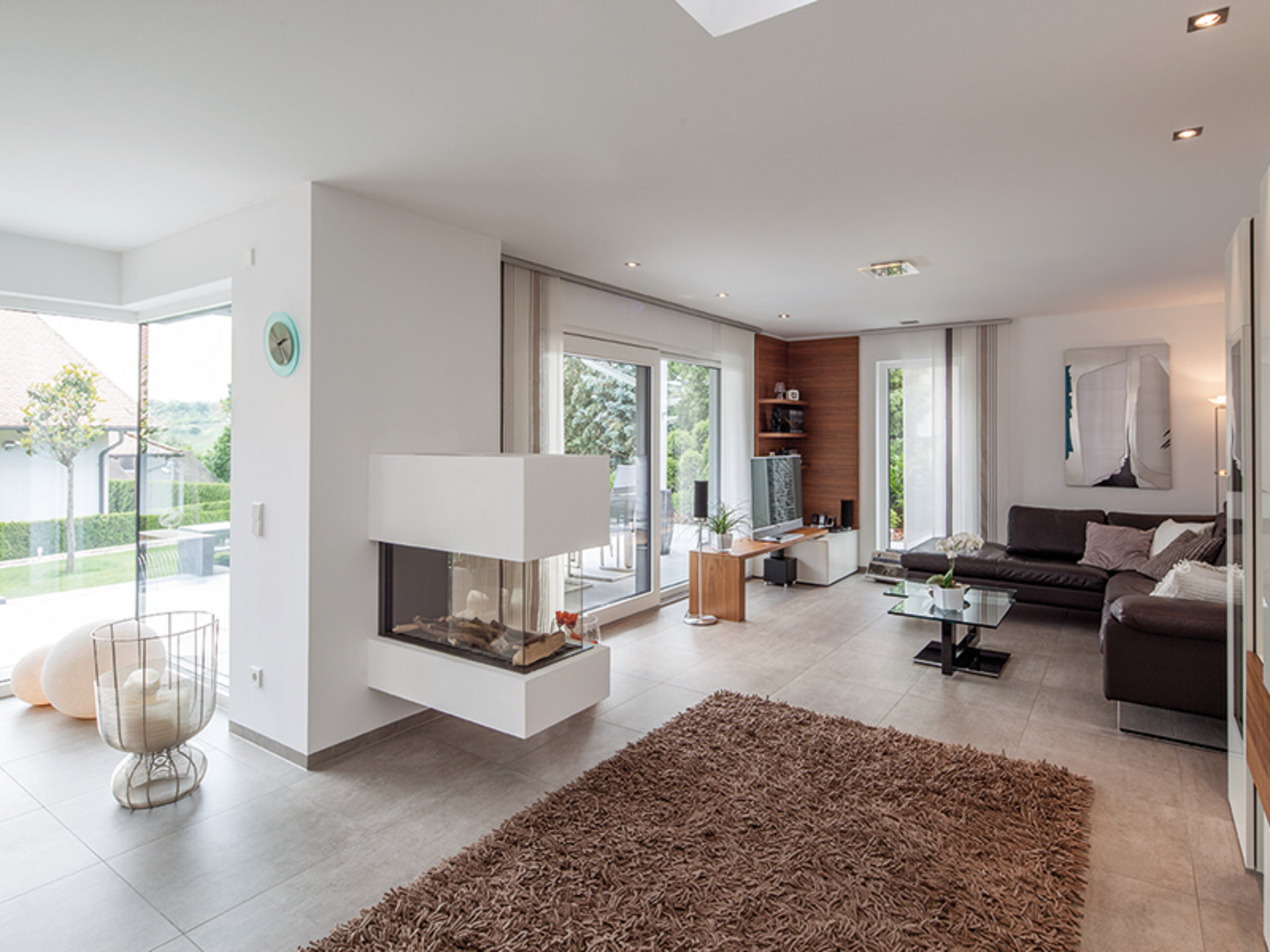 BAUMEISTER-HAUS Uthoff – Wohnbereich mit Kaminofen und großen Glasflächen in Richtung Garten