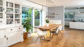 Stilvoll gemütlich wurde der Essbereich mit viel Lichteinfall im Haus Töpfer gestaltet. (Foto: © BAUMEISTER-HAUS) Essbereich mit weißem Schrank und hellen Möbeln