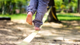 Für ältere Kinder bringt eine Slackline Spaß und Herausforderung gleichermaßen. (Foto: © Maik / stock.adobe.com) Kind balanciert auf Slagline