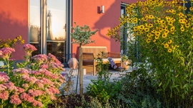 Ein regelmäßig gelockerter und mit biologischem Dünger behandelter Boden bietet die richtige Nährstoffbasis für eine gesunde Pflanze, wie im Garten von Haus Urban. (Foto: BAUMEISTER-HAUS)