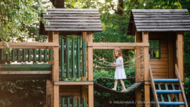 Klettern, Rutschen, Balancieren – hier können Kinder sich richtig austoben. (Foto: © industrieblick / stock.adobe.com) Kind balanciert auf Hängebrücke am Spielturm