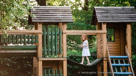 Klettern, Rutschen, Balancieren – hier können Kinder sich richtig austoben. (Foto: © industrieblick / stock.adobe.com) Kind balanciert auf Hängebrücke am Spielturm