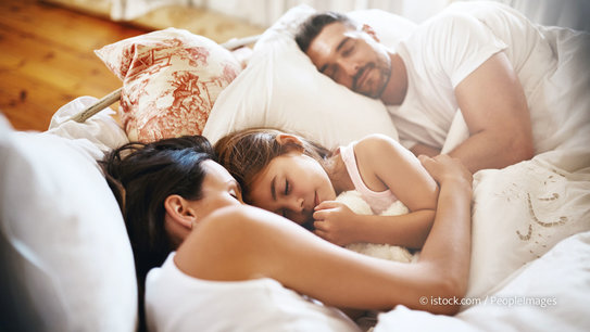 Eltern mit Kind schlafen friedlich im Bett