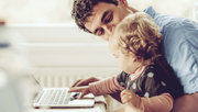 Ein Vater sitzt mit seinem Kind am Laptop und plant die Zukunft