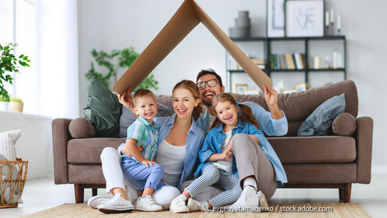 Familie sitzt unter Dach aus Pappe