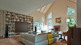 Offener Wohnbereich mit besonderen Fensterformen imposantem Bücherregal