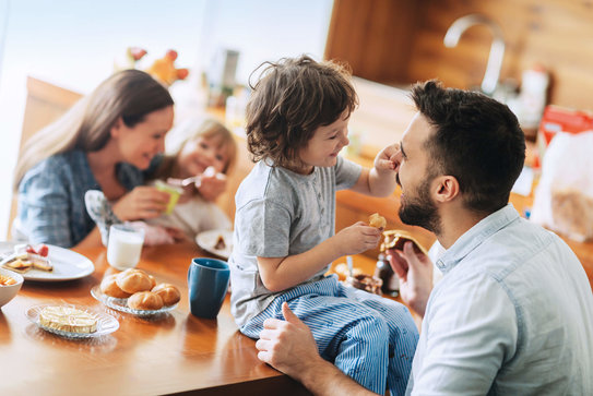 Eine Familie mit 2 Kindern hat ein entspanntes Frühstück in der eigenen gemütlichen Küche
