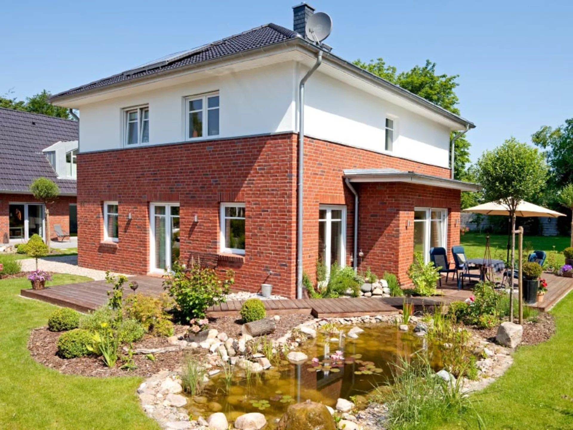 Haus Meinke – Hier bilden Terasse und Teich das Zentrum des Gartens und Beete und Topfpflanzen fügen sich harmonisch ein (Foto: © BAUMEISTER-HAUS)