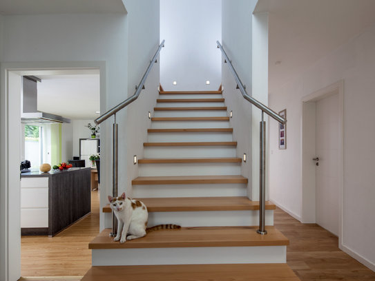 Haus Daniel mit einer effektvoll beleuchteten Treppe und symmetrischen Handläufen (Foto: BAUMEISTER-HAUS)
