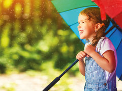 Ein Kind schützt sich mit einem Regenschirm vor Regen