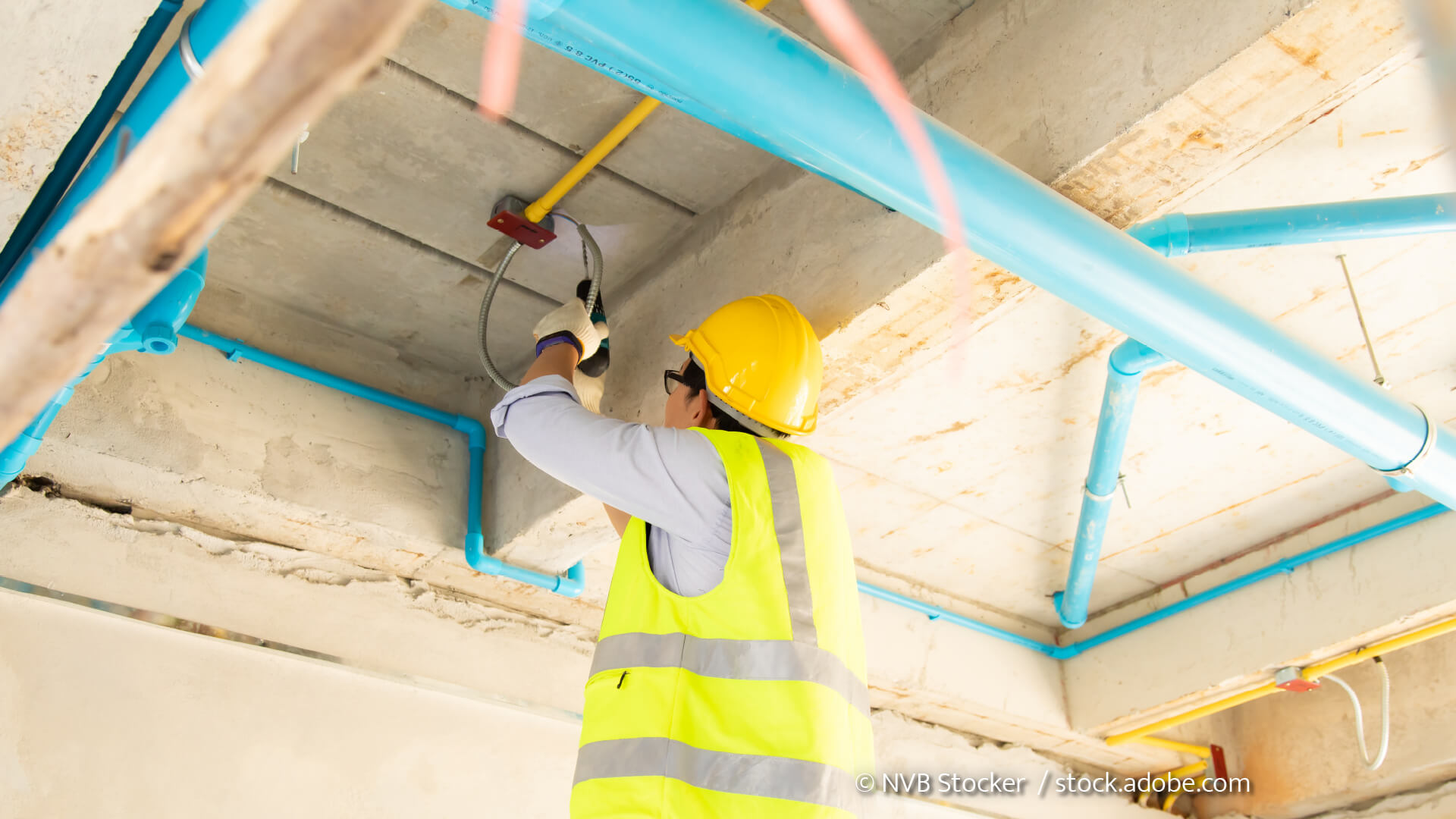 Mann installiert Schläuche und Kabel im Rohbau